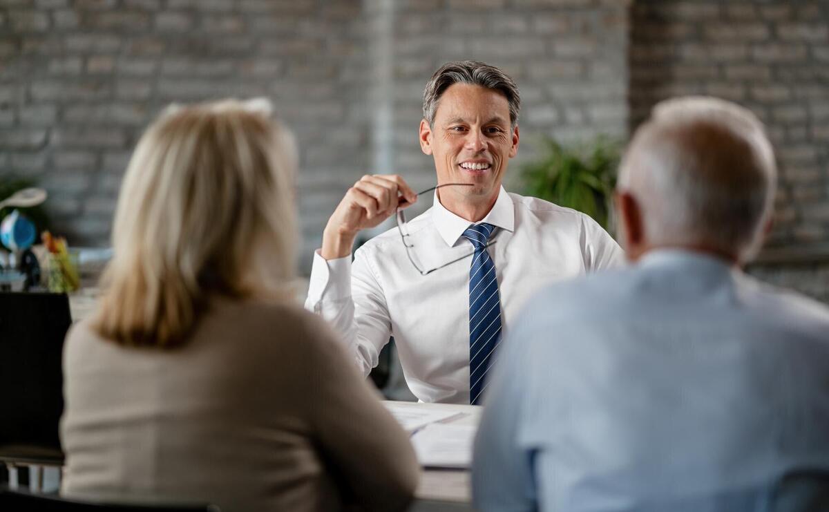 Happy financial advisor communicating with senior couple while having meeting with them in the office