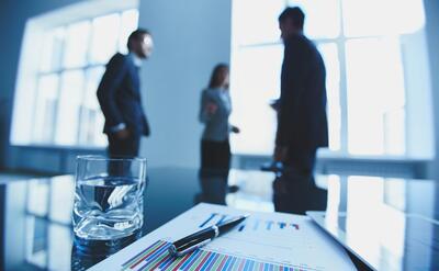 Documents with charts and a glass of water on the desk