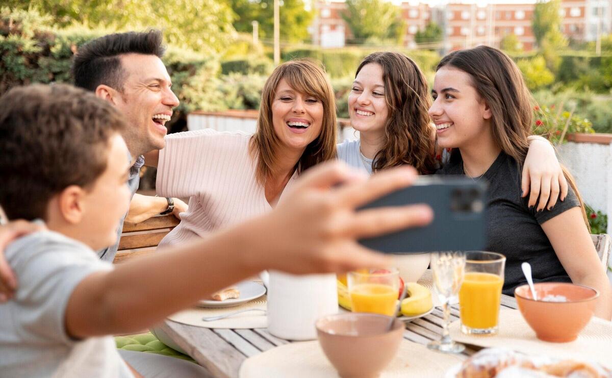 Child taking selfie of family having lunch outdoors together