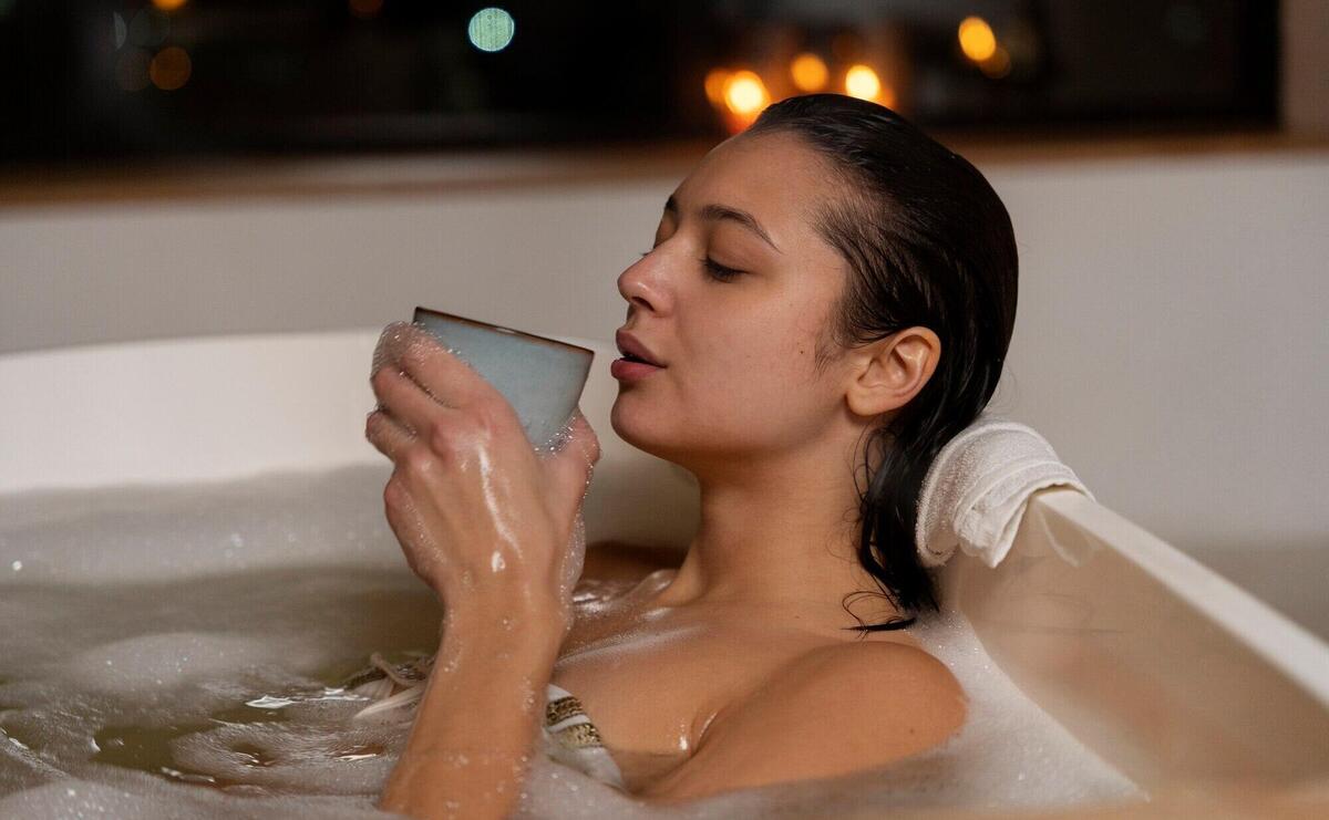 Young woman drinking coffee and relaxing while taking a bath