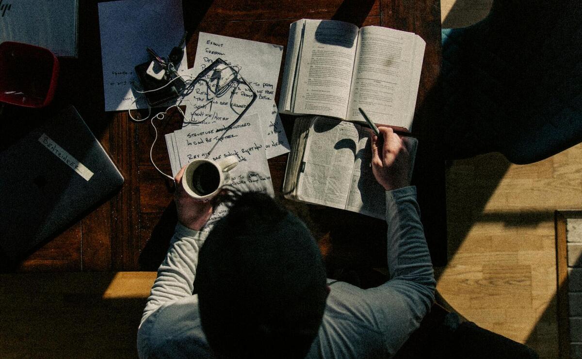 man in black long sleeve shirt writing on white paper