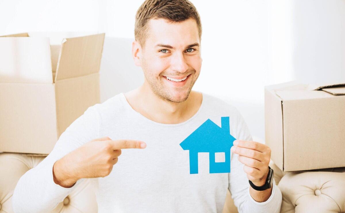 Smiling man pointing at paper house