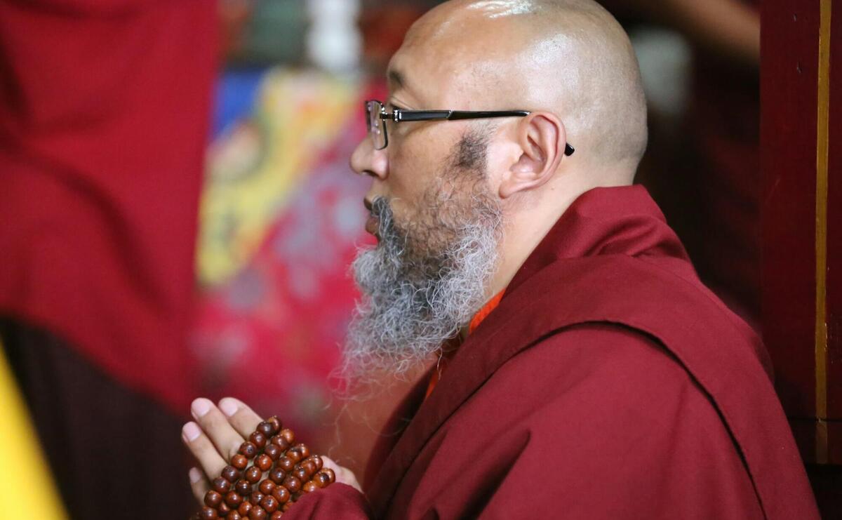 a man with a long beard and glasses is holding a beaded object