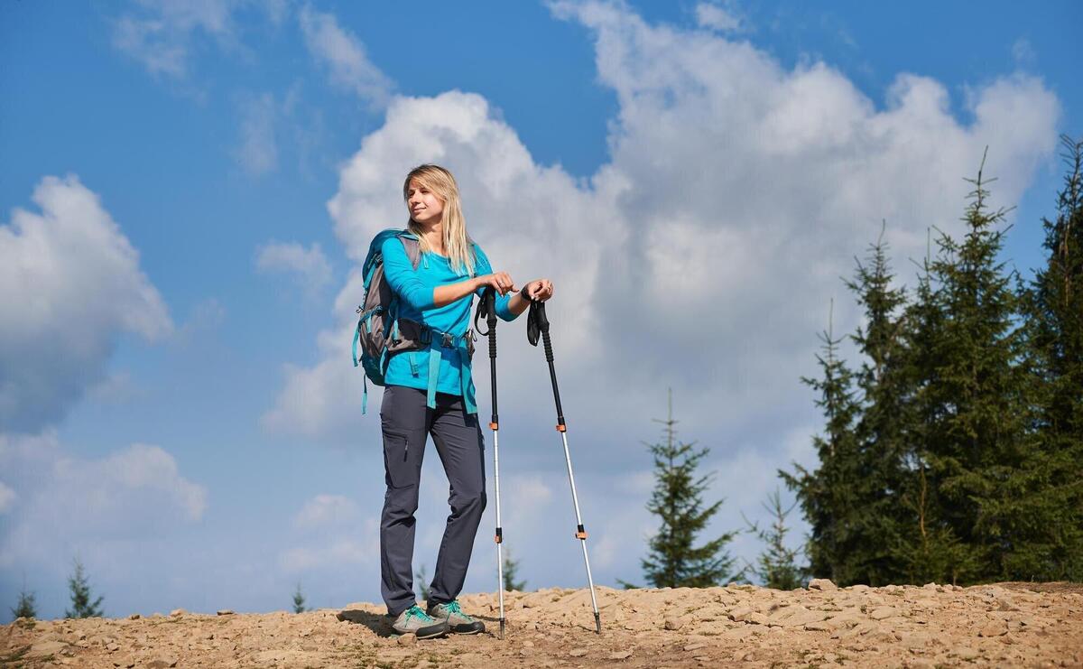 Female hiker standing on mountain road against blue cloudy sky