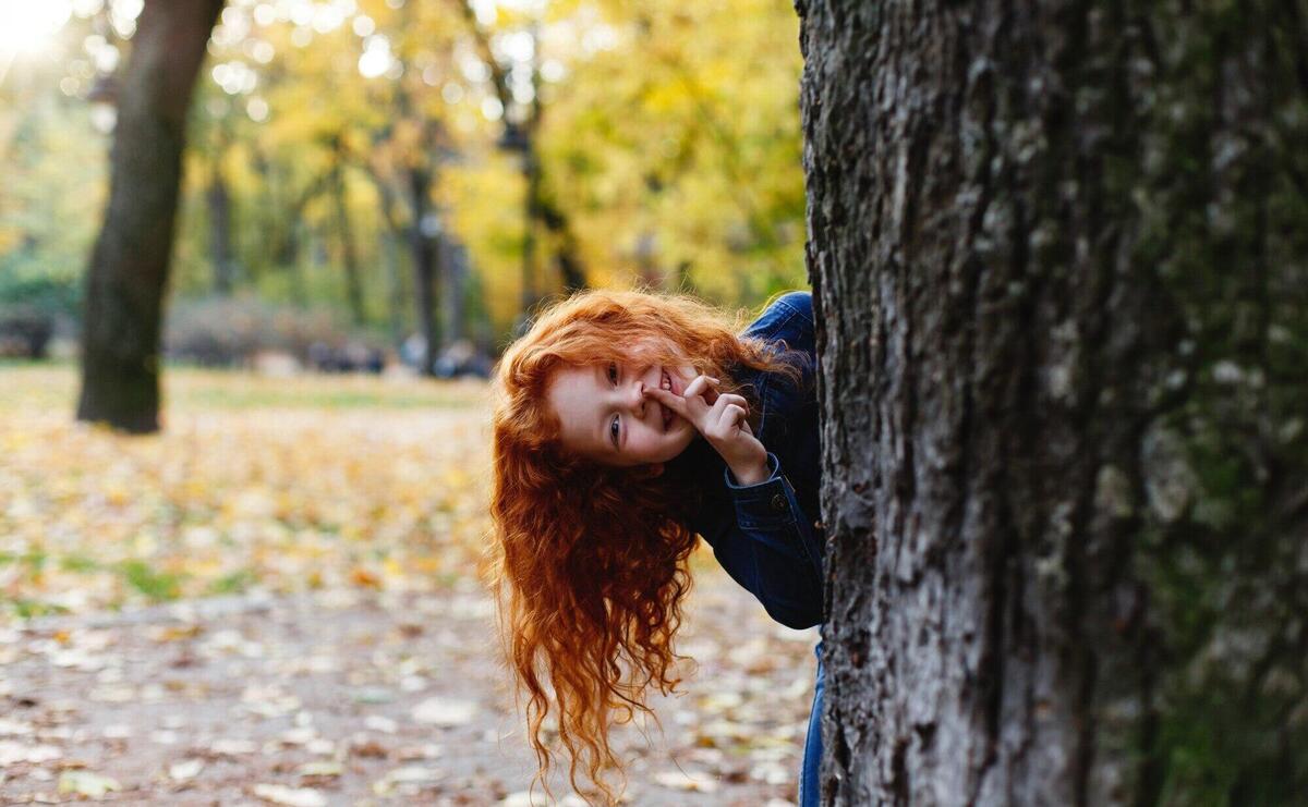 Autumn vibes, child portrait. Charming and red hair little girl looks happy walking and playing on t