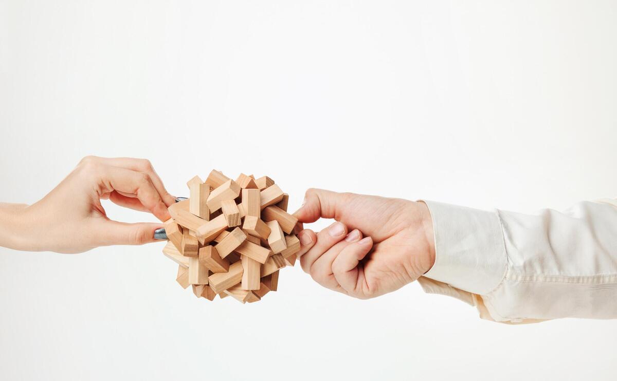 Wooden puzzle in hands isolated on white.