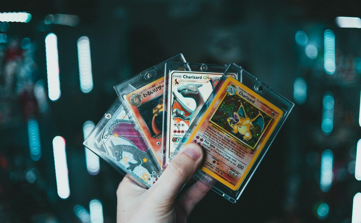 A hand holds collectible Charizard Pokemon cards with a blurred bokeh background. Perfect for trading card enthusiasts.