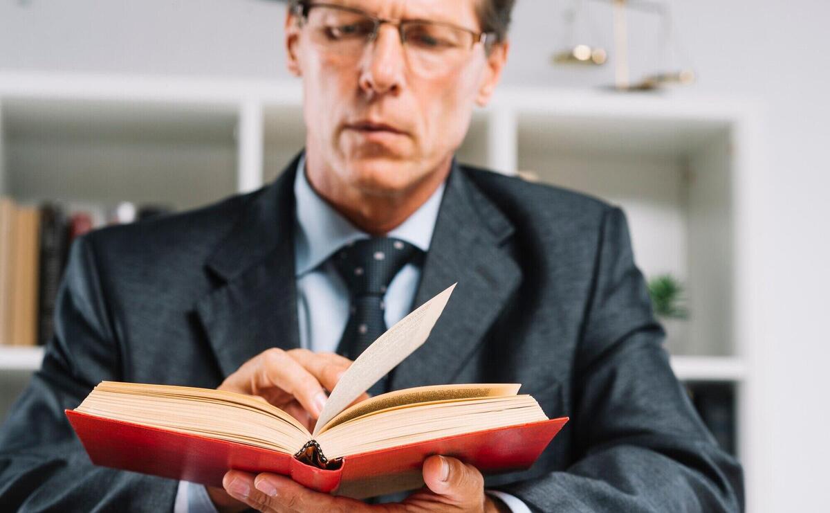 Mature male judge reading book in courtroom