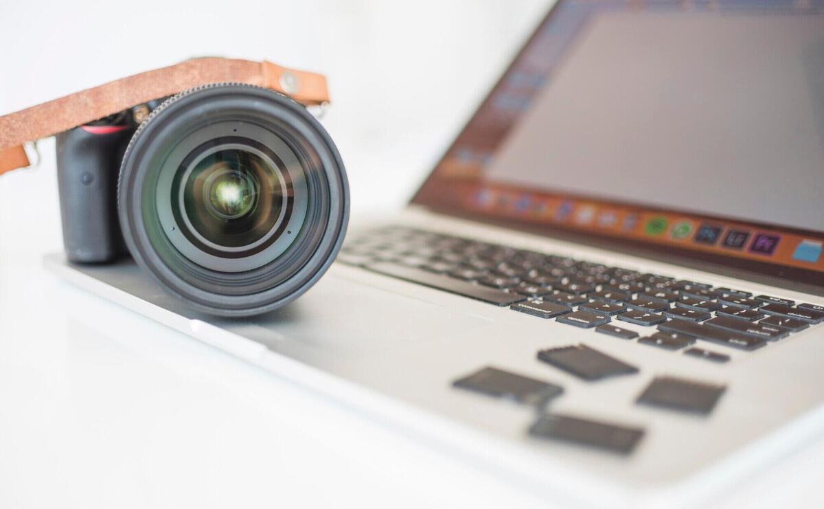 Professional modern camera and memory cards on laptop