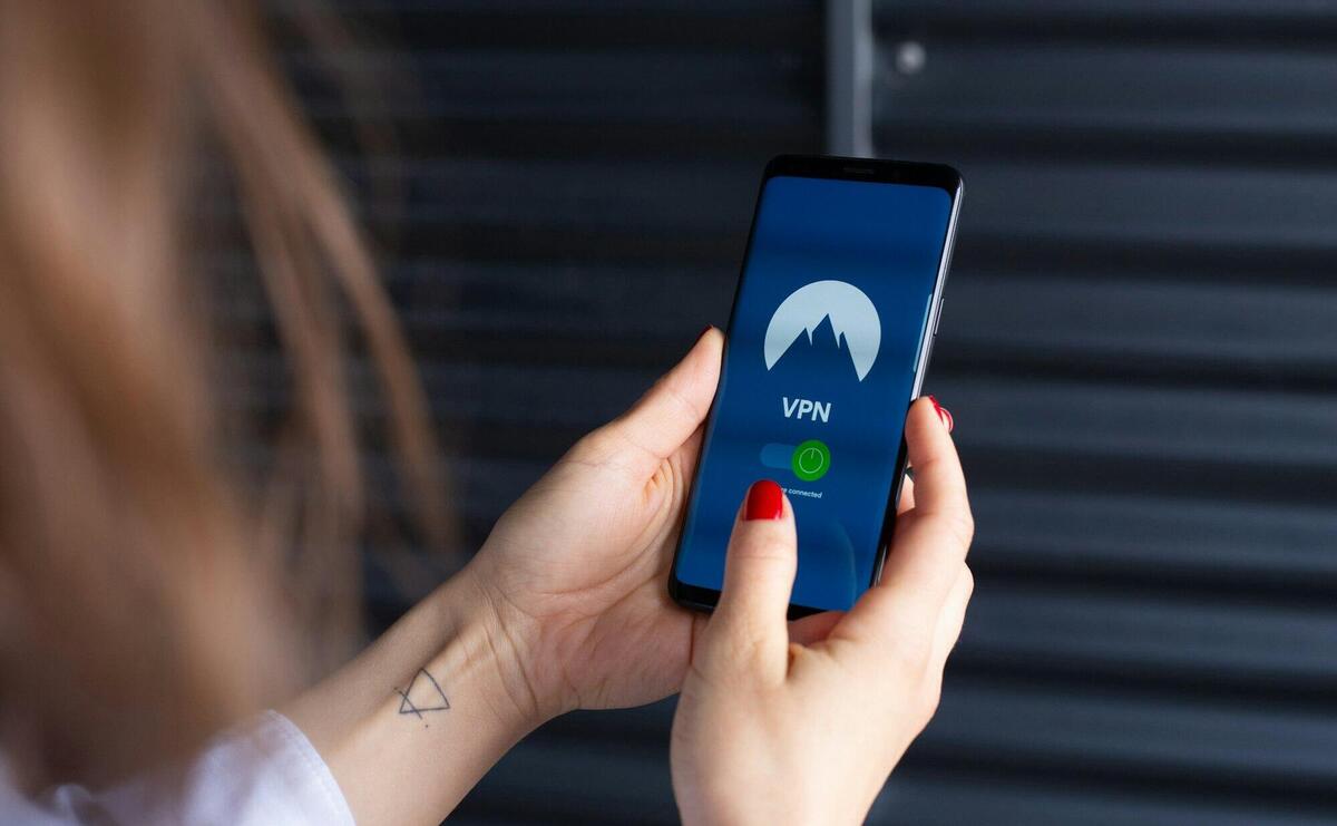 Close-up of a woman's hands using a VPN app on a smartphone, emphasizing digital security.