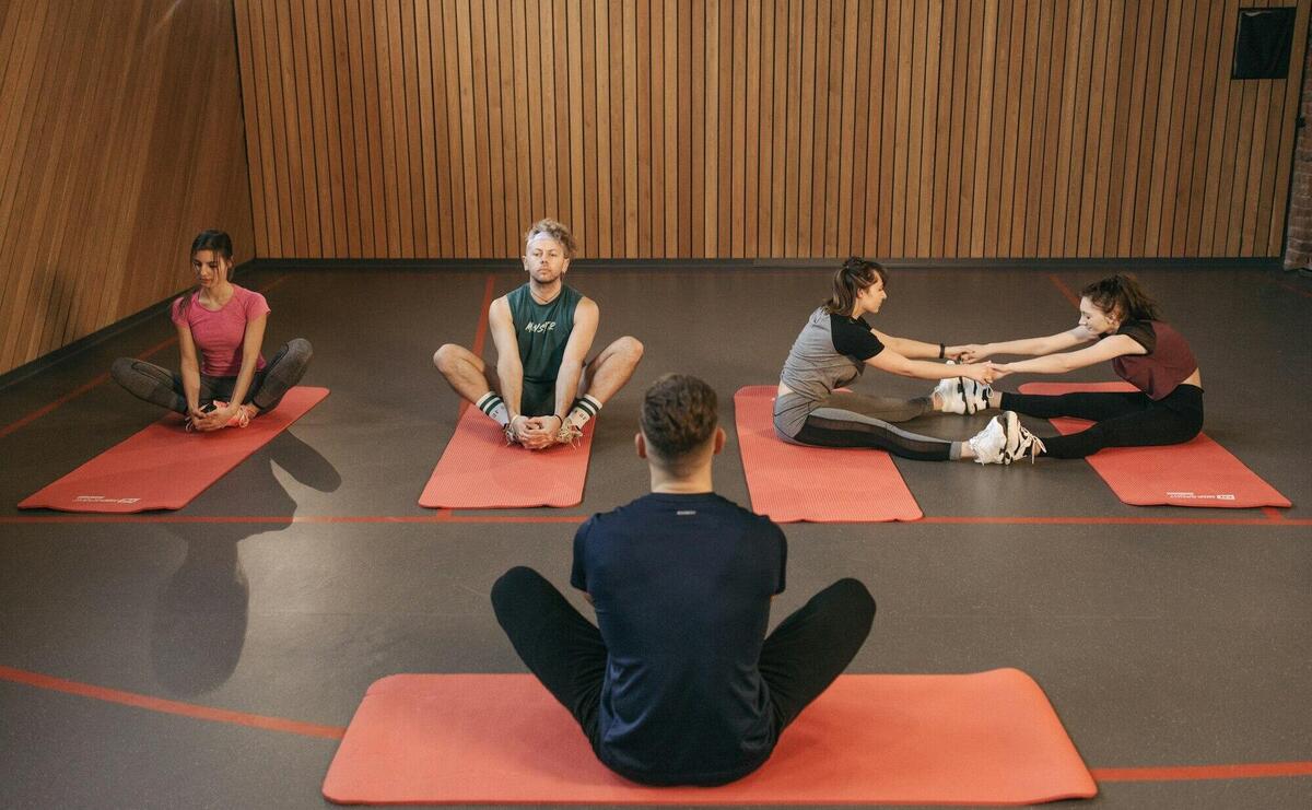 People engaging in a yoga class with red mats in an indoor wooden studio.