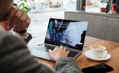 Cropped image of businessman sitting by the table in cafe and analyzing indicators