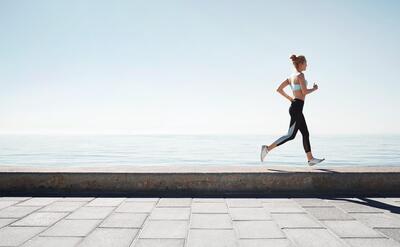 Jogging young woman running on shore