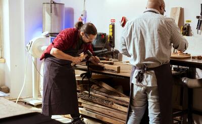 Manufacturer carving wood using chisel and hammer wearing safety glasses