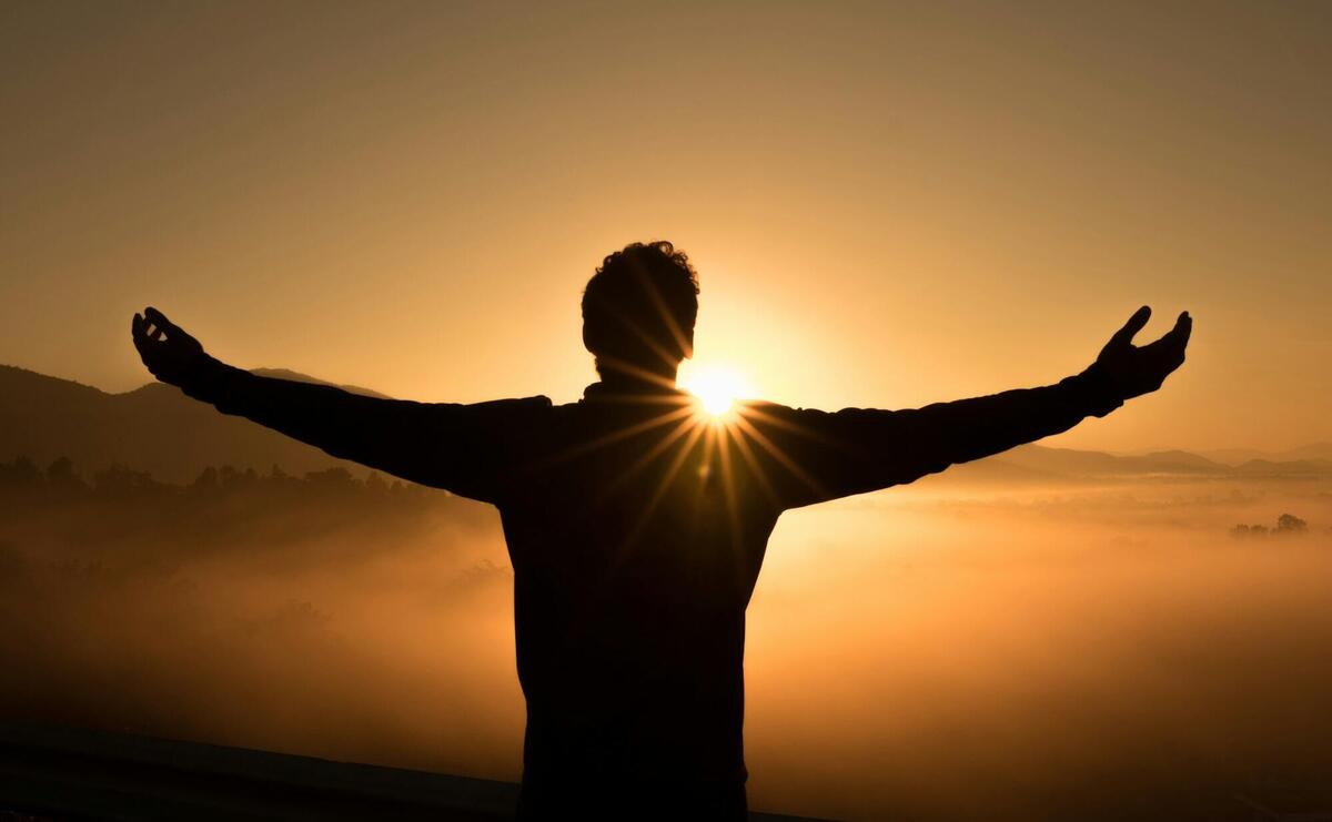 silhouette photo of man on cliff during sunset