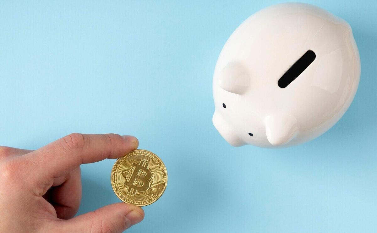 Top view piggy bank with person holding a bitcoin