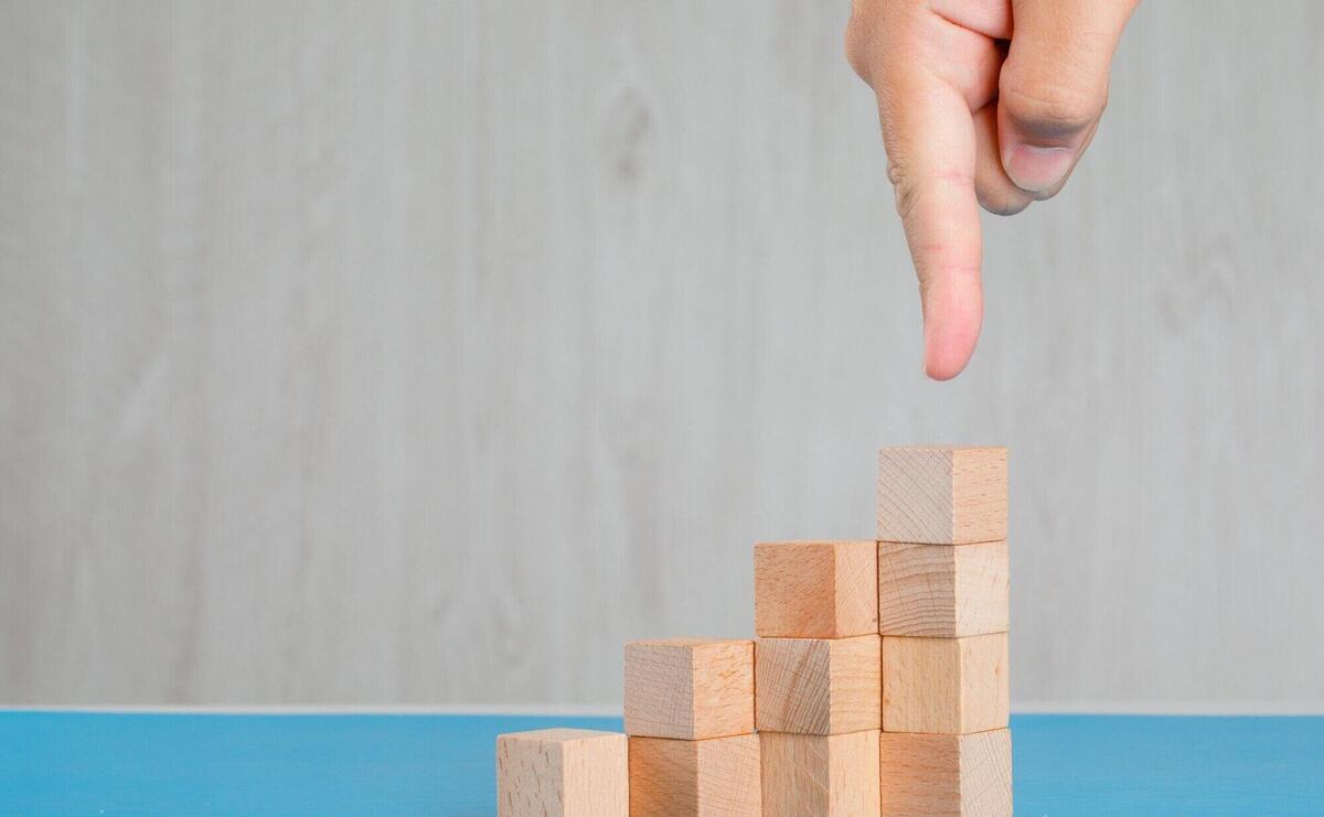 Business success concept on blue and grey table side view. finger showing stack of wooden cubes.