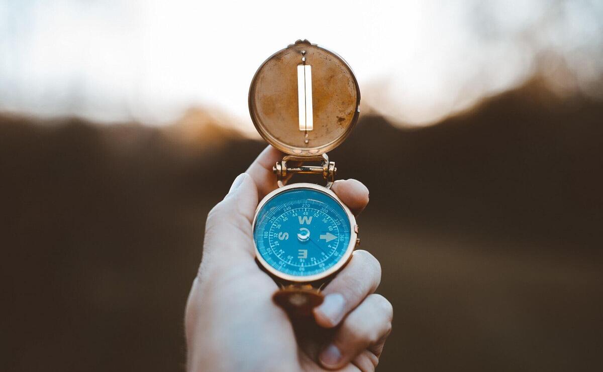 Closeup shot of a person holding a compass with a burred background