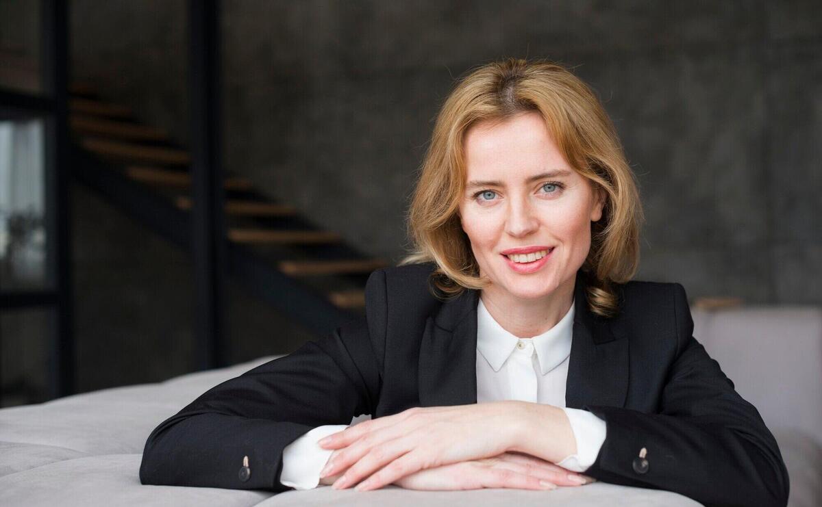 Blond business woman sitting on couch and smiling 