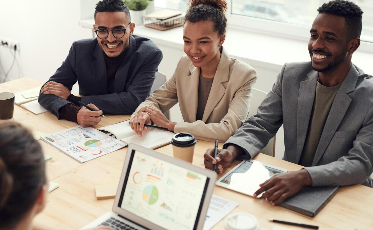 Photo of Three People Smiling While Having a Meeting