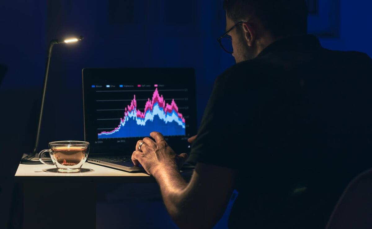 Man trading browsing online stock investments at night