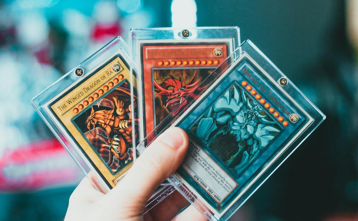 Close-up of a hand holding collectible trading cards in protective cases.