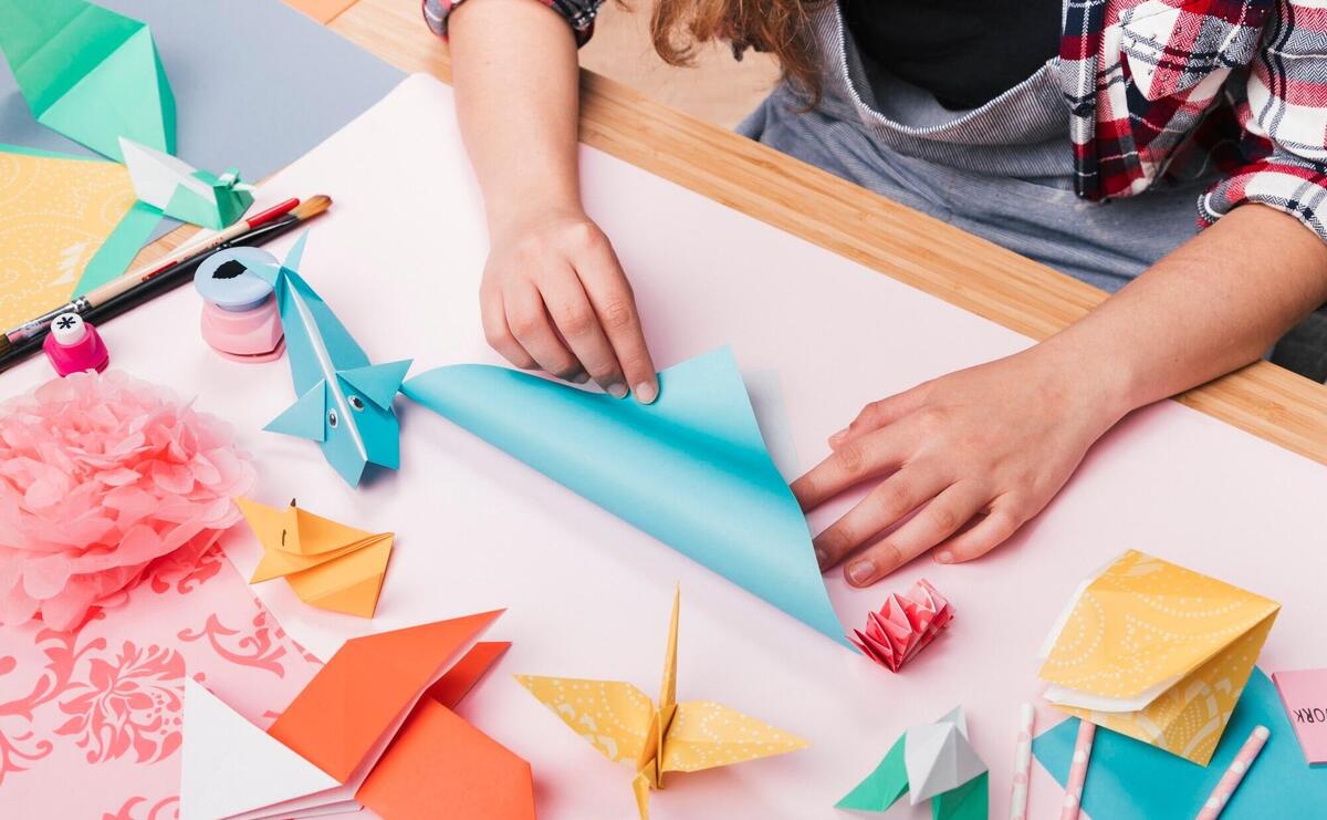 Female artist folding origami paper for making beautiful craft