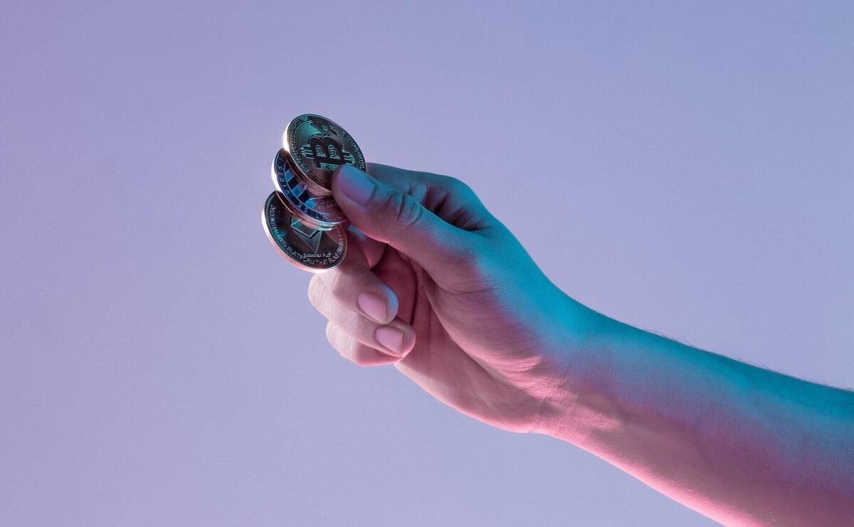 Male hand with golden bitcoin on blue background