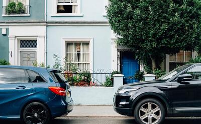 Two parked cars in front of an apartment entrance