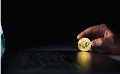 Bitcoin coin near laptop on black background Finance and crypto money concept