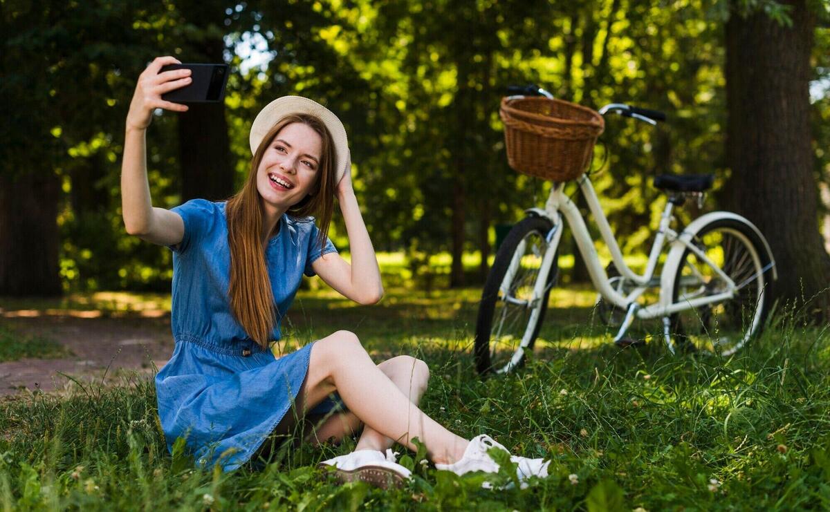 Woman sitting on grass taking a selfie