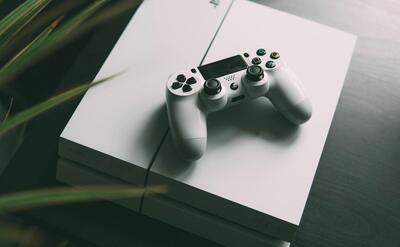 selective focus photography of white Sony PS4 console with wireless controller