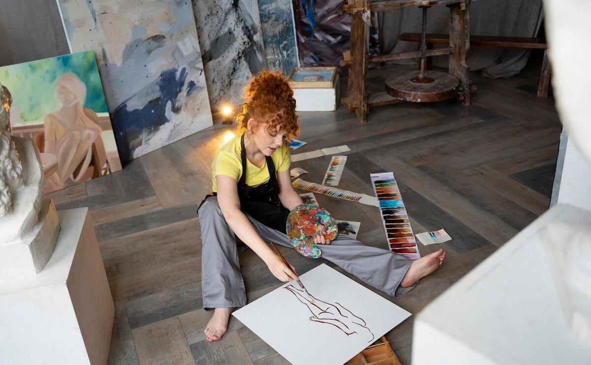 Full shot woman on floor painting with brush