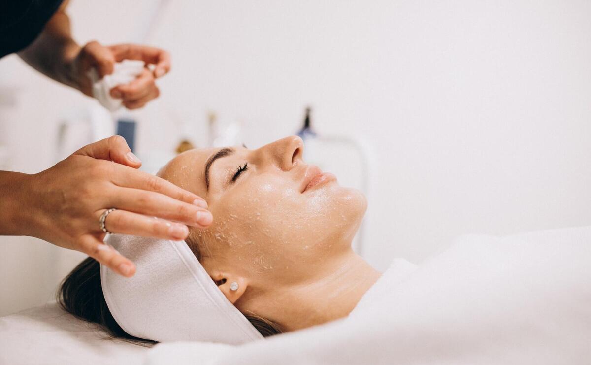 Cosmetologist cleaning face of a woman in a beauty salon