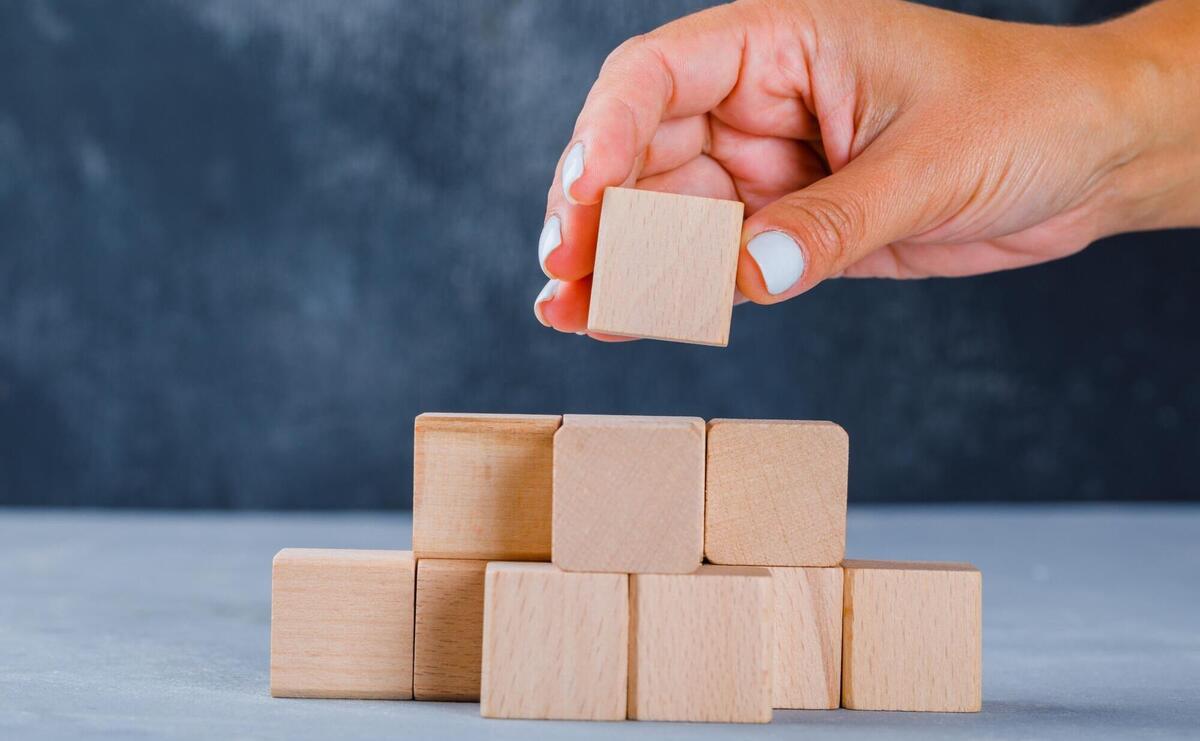 Hand putting and stacking wooden cubes.