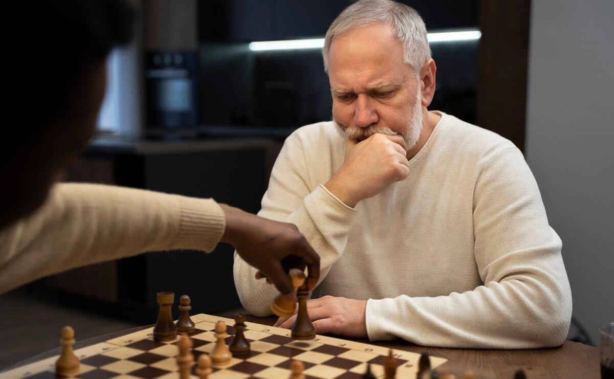 Side view young and old men playing chess