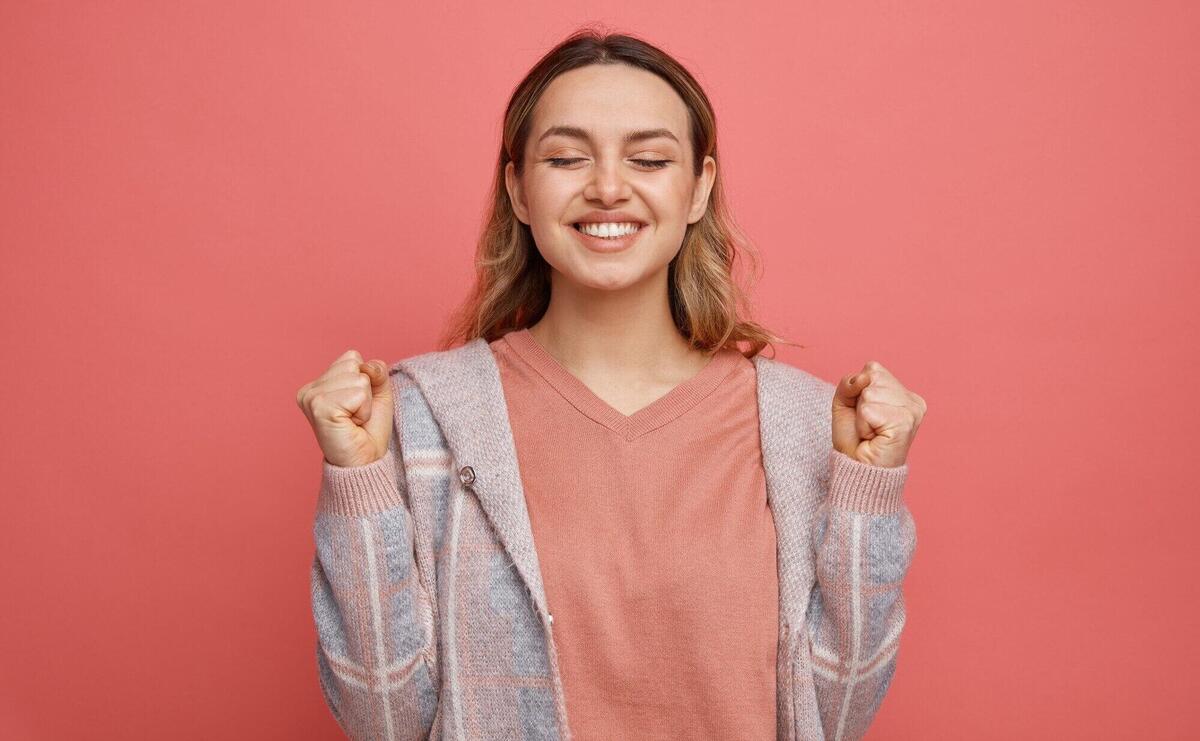 Joyful young girl doing yes gesture with closed eyes 