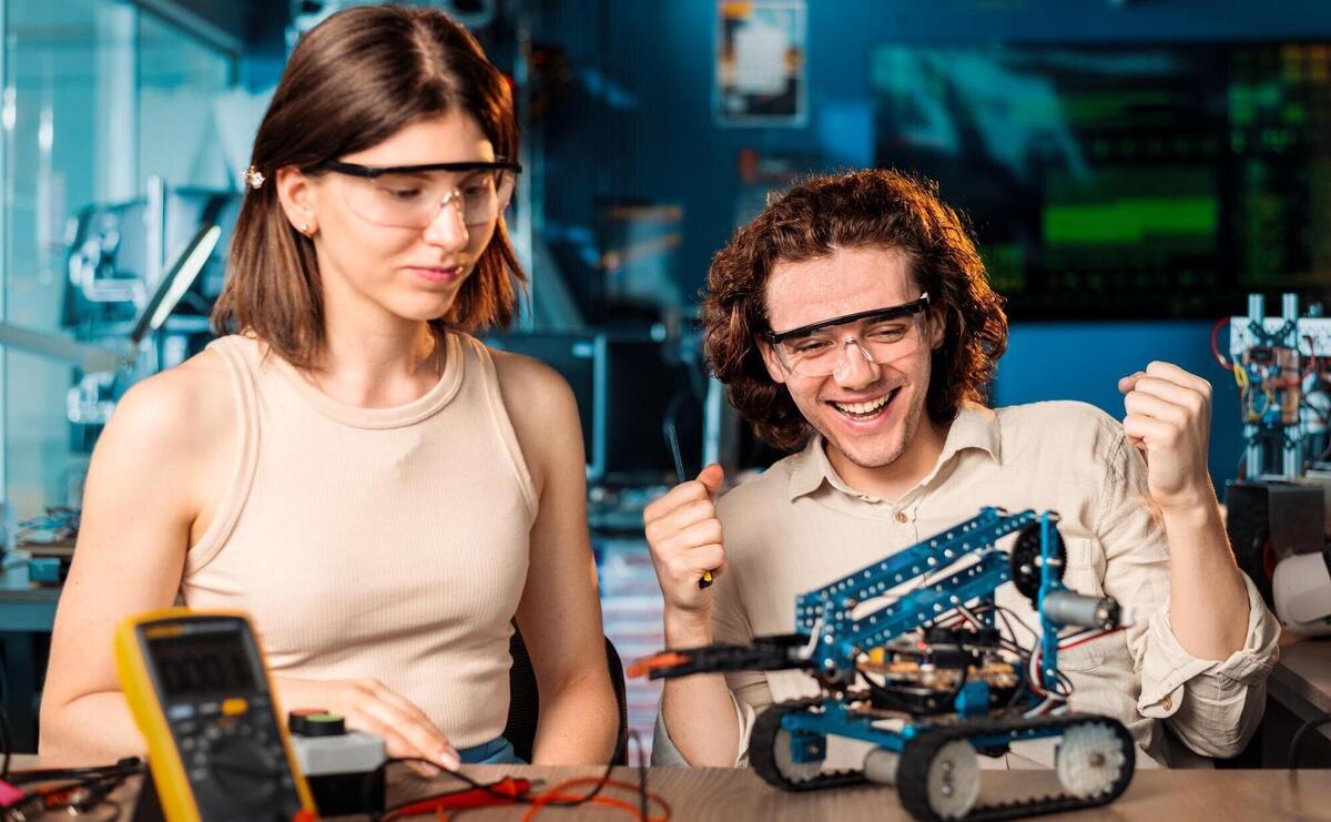 Excited young man and woman in protective glasses doing experiments in robotics in a laboratory