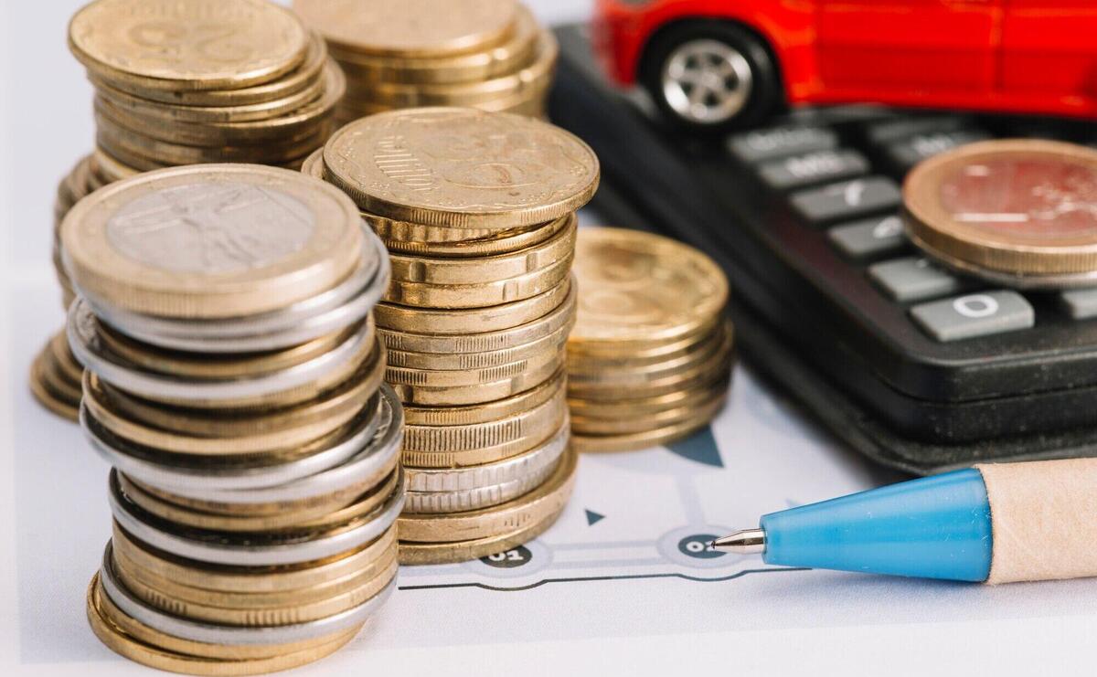 Close-up of stacked coins; pen and calculator