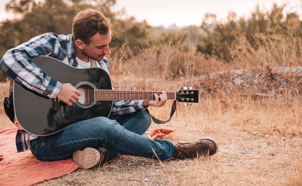 Man sitting on blanket playing guitar