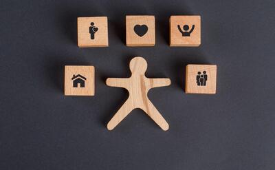 Family concept with icons on wooden cubes, human figure on dark grey table flat lay.