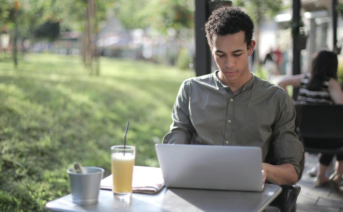 Focused black male freelancer using laptop in street cafe