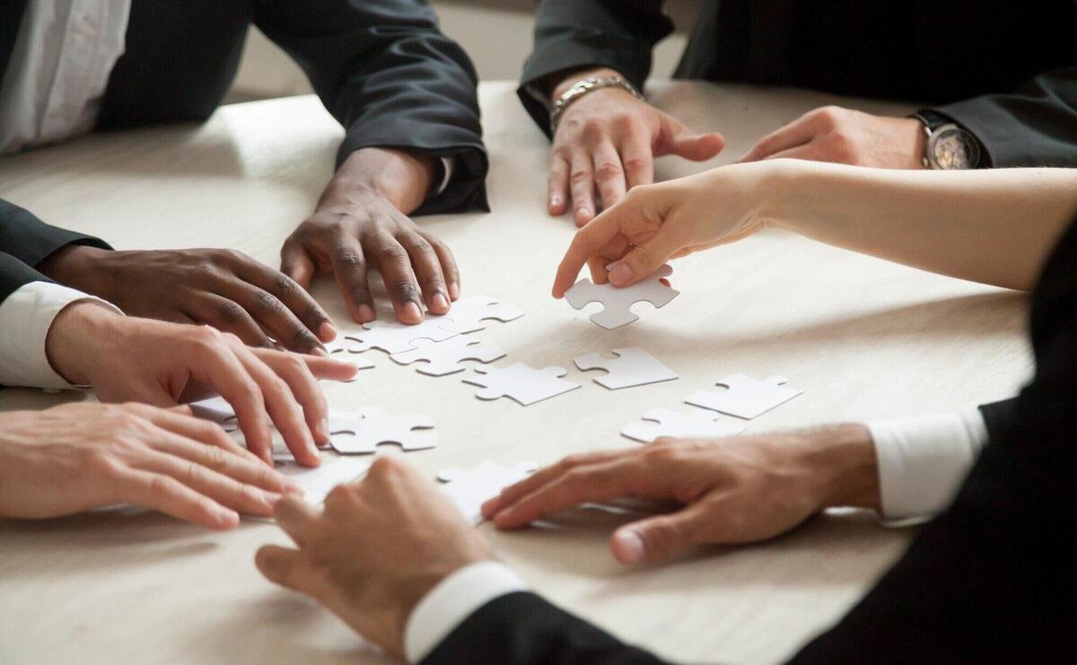 Close up of multiethnic team solving blank puzzle game.