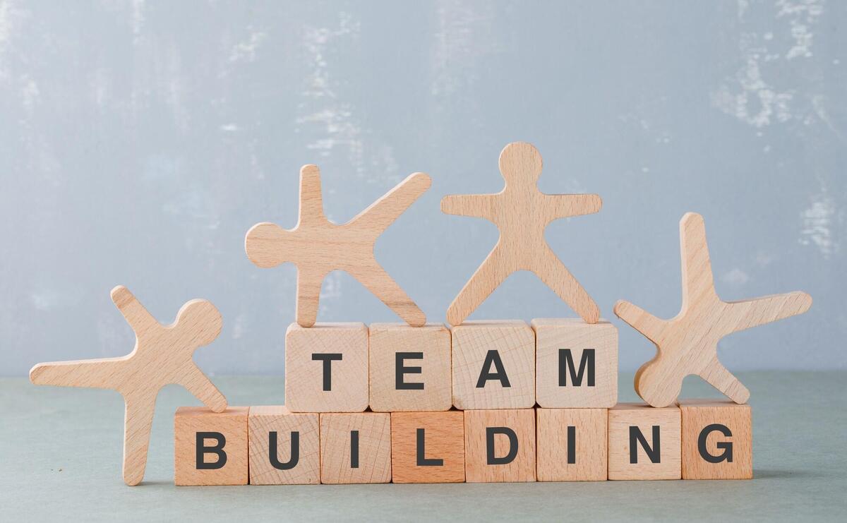 Team building concept with wooden blocks, wooden human figures on it side view.