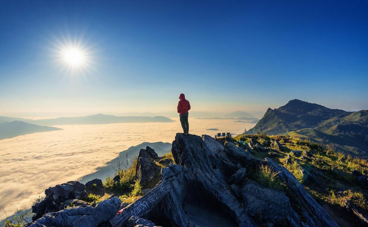 Traveler standing on the rock, Doi pha tang and morning fog in Chiang rai, Thailand.