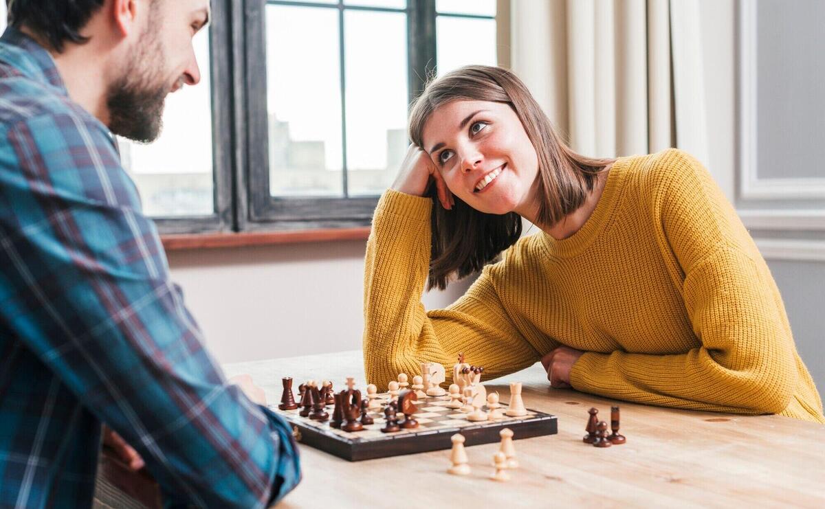 Young couple sitting together playing the chess at home