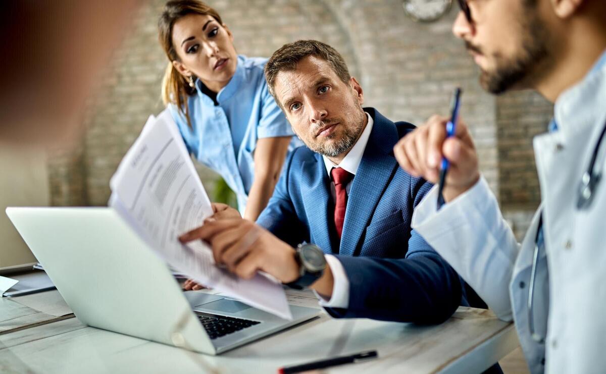 Mid adult businessman and group of doctors analyzing paperwork while having a meeting in the office