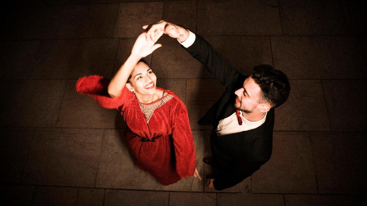 Young man holding hand of dancing charming happy woman