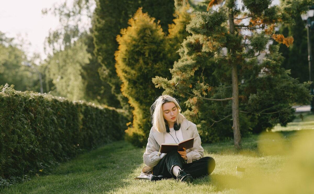 Blonde sitting on a grass with headphones