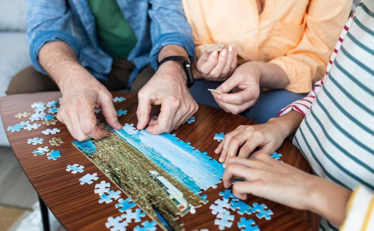 Close up people doing puzzle together